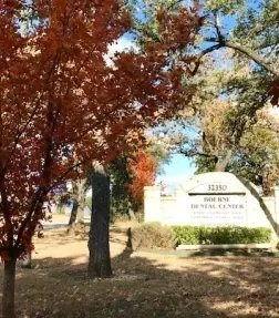 An autumn tree in red leaf beside the Boerne Dental Center sign.