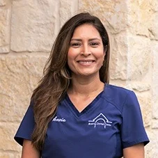 Annie, Registered Dental Hygienist at Boerne Dental Center, in navy scrubs against a limestone wall.