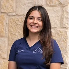 Cassandra, Registered Dental Assistant at Boerne Dental Center, in navy scrubs against a limestone wall.