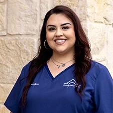 Jocelyne, Front Office at Boerne Dental Center, in navy scrubs against a limestone wall.