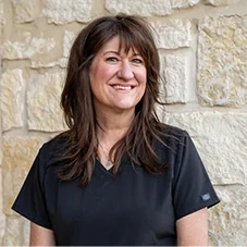Julie, Front Office at Boerne Dental Center, in navy scrubs against a limestone wall.