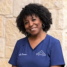 Laverne, Registered Dental Assistant at Boerne Dental Center, in navy scrubs against a limestone wall.