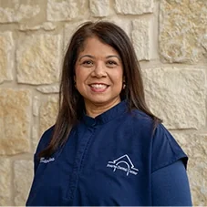 Mara, State Registered Dental Hygienist at Boerne Dental Center, in navy scrubs against a limestone wall.