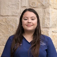 Seleny, State Registered Dental Hygienist at Boerne Dental Center, in navy scrubs against a limestone wall.